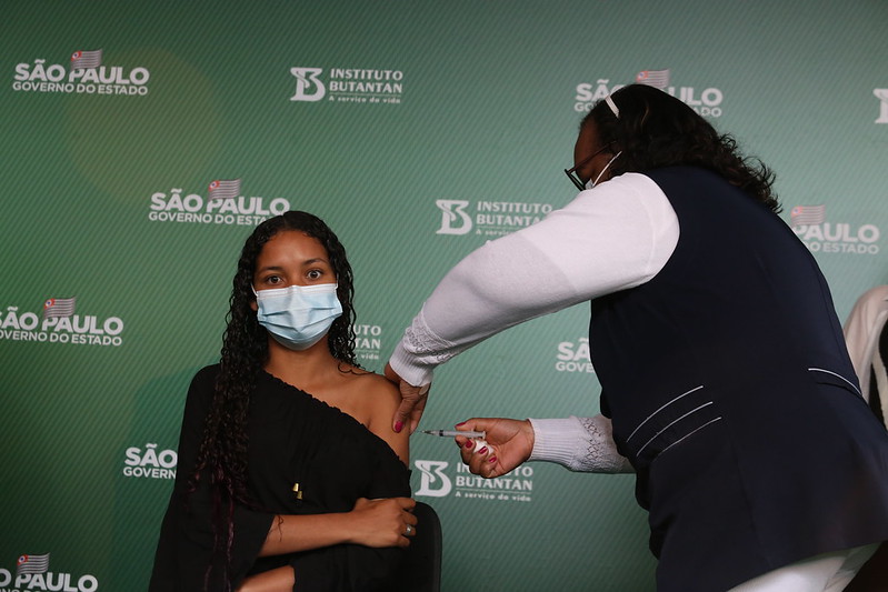 Imagem mostra enfermeira aplicando vacina em jovem