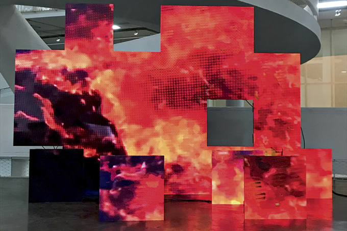 A imagem mostra um painel de telas de led. Cada uma delas compõe a imagem de chamas em fundo preto. Elas estão espalhadas em um plano, sem uniformidade.