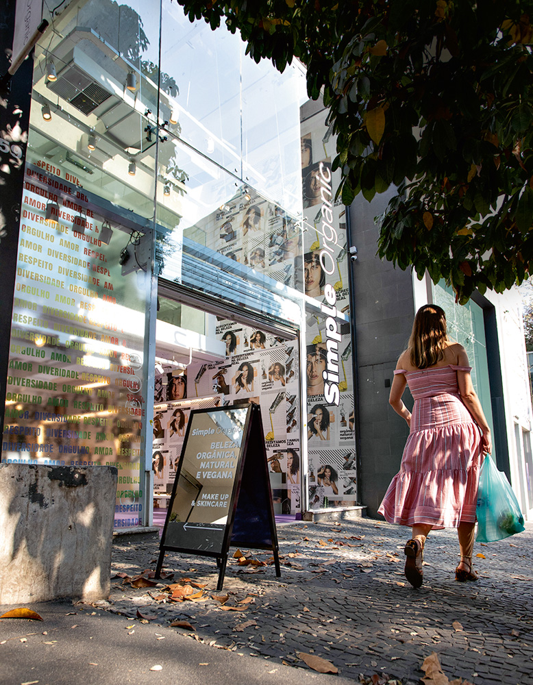 A imagem mostra a fachada da Simple Organic. Há uma parede vidro e é possível ver parcialmente o interior da loja devido ao reflexo.