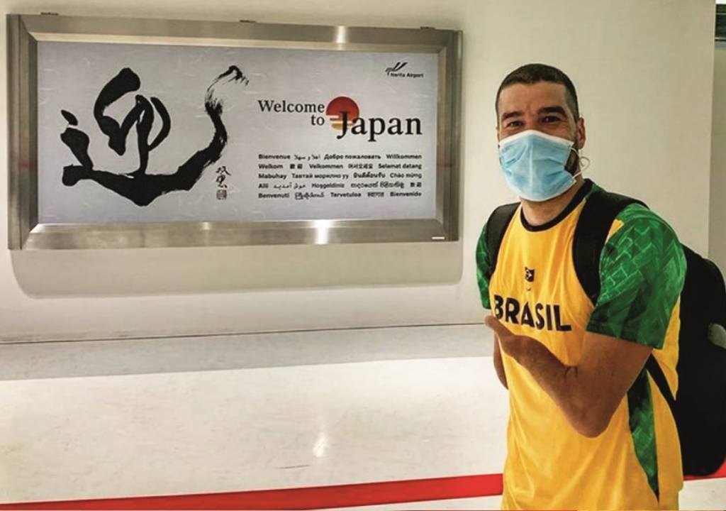 O atleta Daniel Dias posa em frente a uma placa escrito "Bem-vindo ao Japão"
