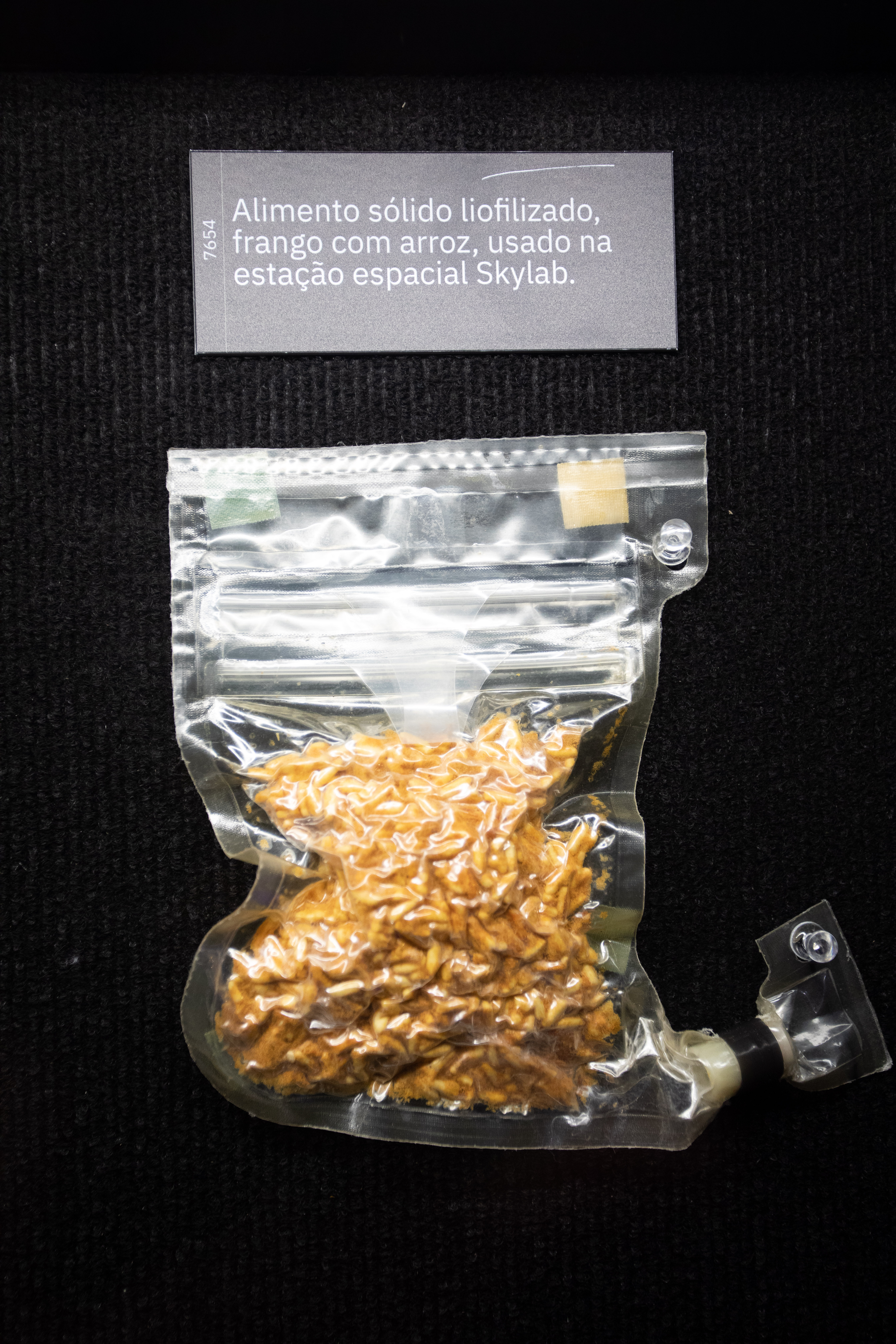 Exposição Space Adventure, Shopping Eldorado (Leo Martins (21) Saco hermeticamente selado guarda alimento sólido de cor amarelada.