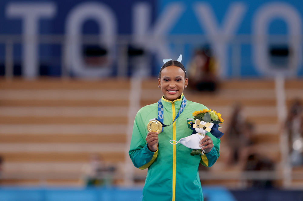 A imagem mostra Rebeca segurando a medalha de ouro no pódio