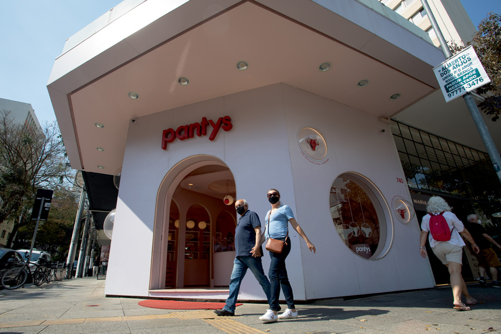 fachada da loja pantys, com formato de quadriláteros e pintada de branco, com pessoas passando na frente