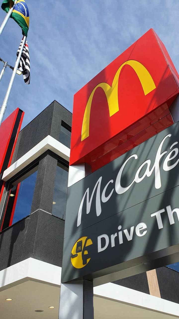 Logotipo do McCafé e McDonald's aparece na foto ao lado de bandeira do Brasil.