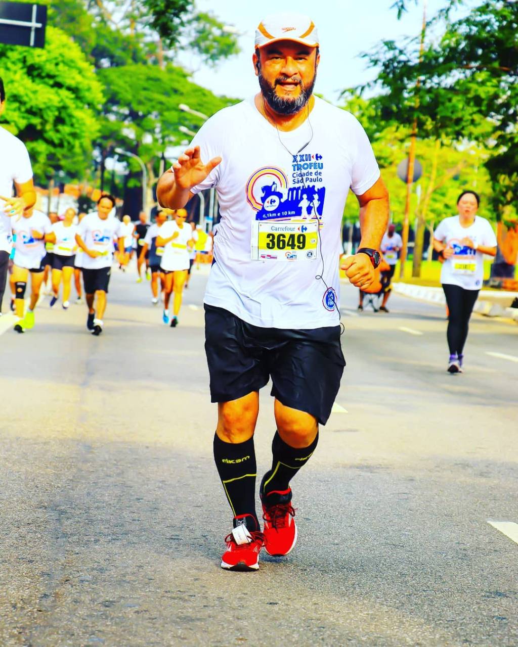 A imagem mostra Rodolfo, em uma maratona, correndo em uma rua. Ele está de boné e roupas esportivas.