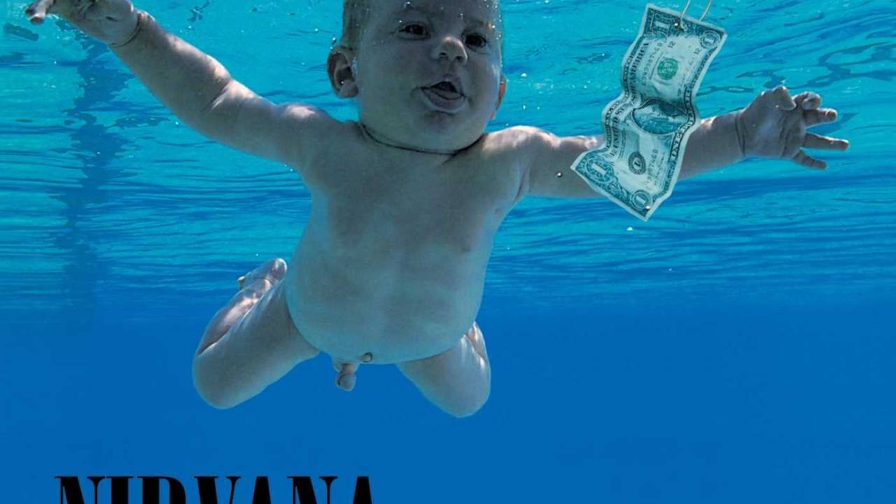 A imagem mostra a capa do álbum Nevermind. Na foto que ilustra o disco, há um bebê nu, dentro de uma piscina. Em sua frente, uma nota de dólar presa a uma isca de pesca.