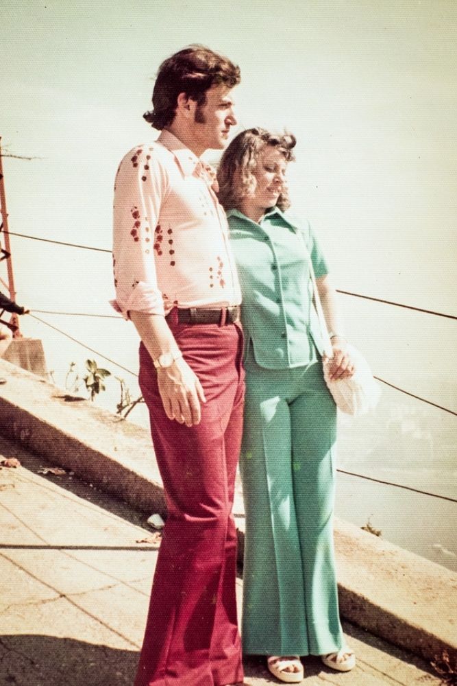 vera e jeri em uma beirada de plataforma, olhando para o horizonte. eles estão com vestimentas estilo anos 80