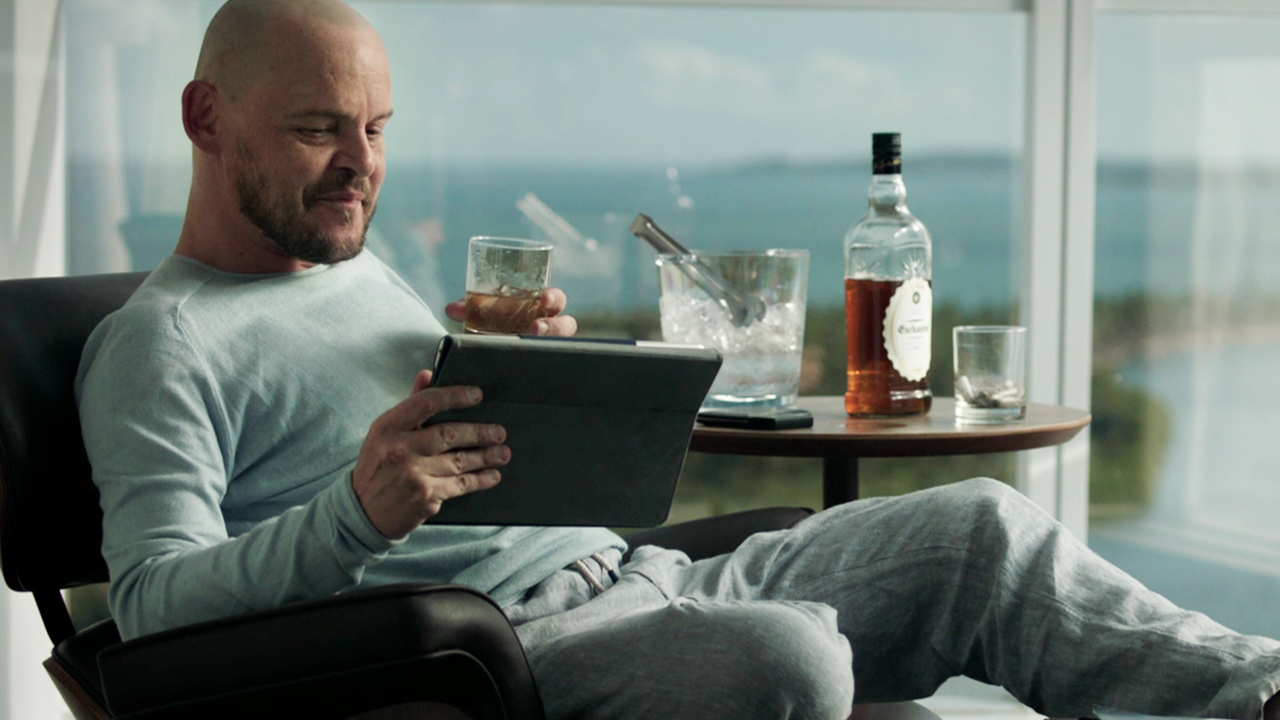 Na imagem, o ator Matheus Nachtergaele está sentado olhando para um tablet