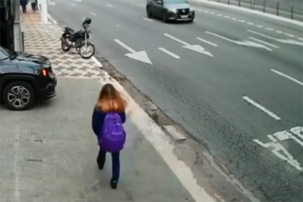 Trecho de vídeo mostra jovem andando pela calçada instantes antes de motoqueiro aparecer na contramão e levar celular das mãos da adolescente