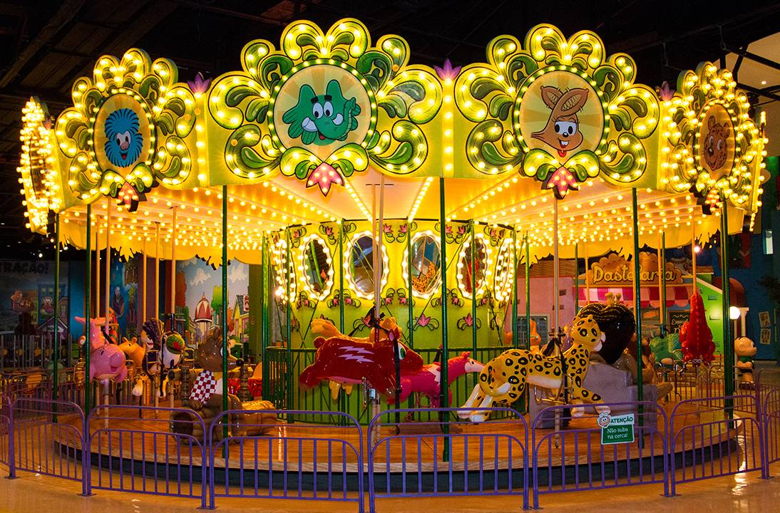 Um carrossel infantil estampado com vários personagens da Turma da Mônica. Ele é bem iluminado