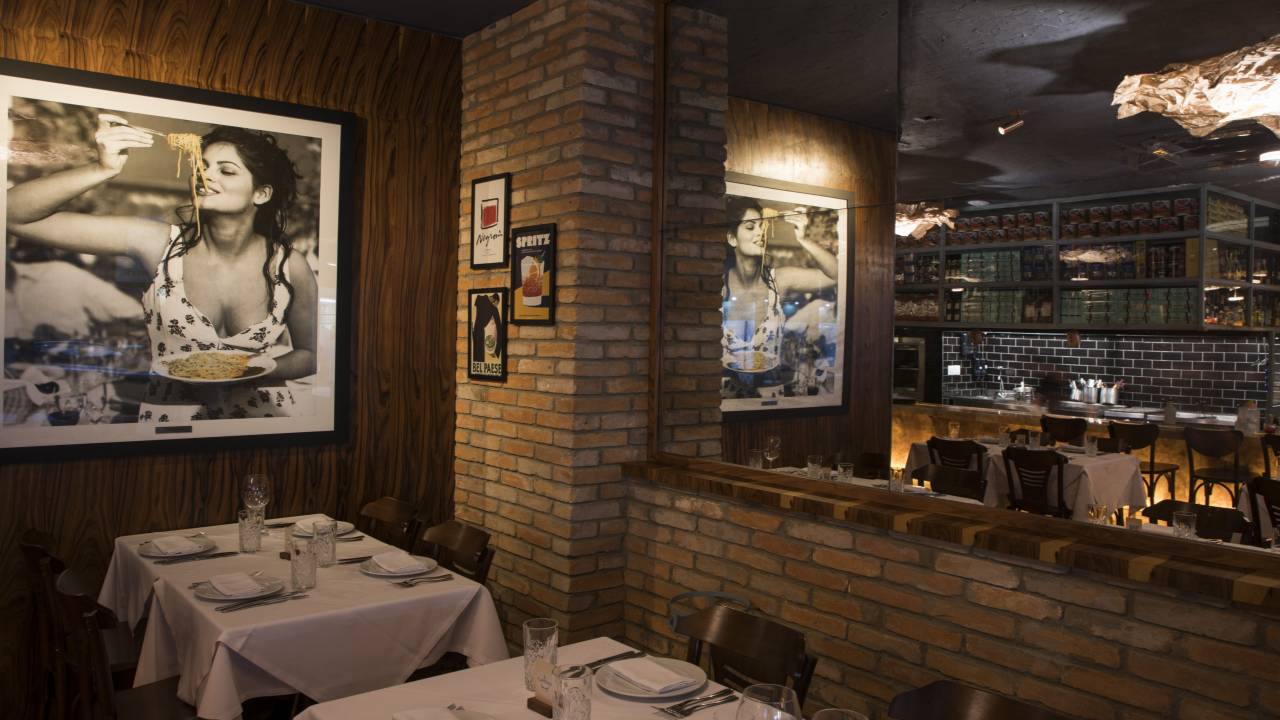 Ambiente de restaurante com quadros na parede e mesas com toalhas brancas