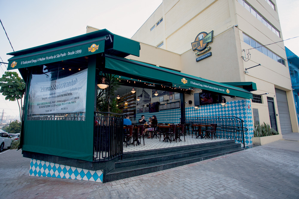 A imagem mostra mostra o bar do Juarez em uma esquina, com o toldo aberto para a rua.