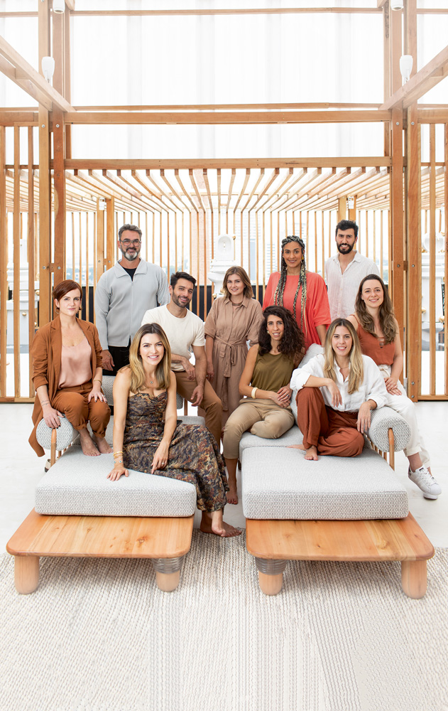 A imagem mostra os arquitetos participantes da CASACOR 2021. Eles estão distribuídos em dois sofás e alguns em pé.
