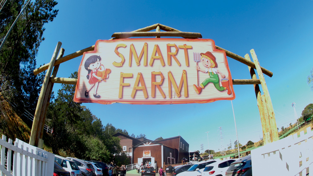 Placa da fazendinha "Smart Farm". Dá para ver um céu azul ao fundo