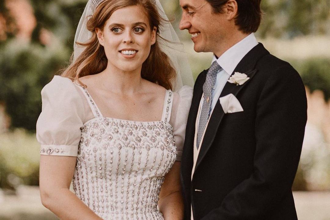 A imagem mostra a princesa com um véu de noiva com as mãos dadas com Edoardo e o fundo desfocado. Ambos estão rindo.