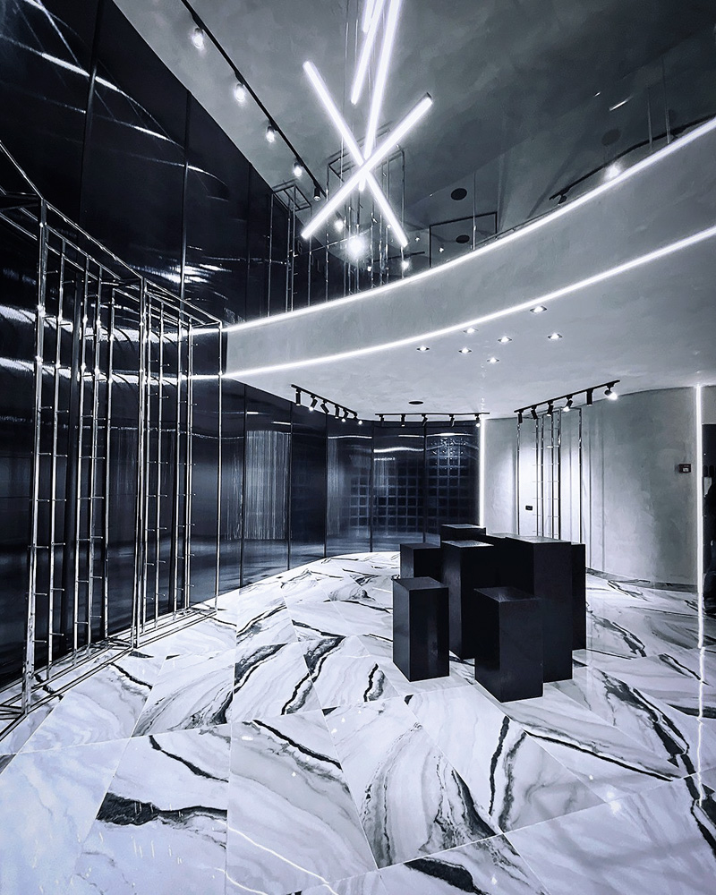 Guadalupe Store (3).jpg Um espaço de uma loja. A decoração é toda em azul bem escuro e branco. Há algumas colunas pretas no centro do espaço, que é bem moderno, mas não está com roupas nem cabides etc