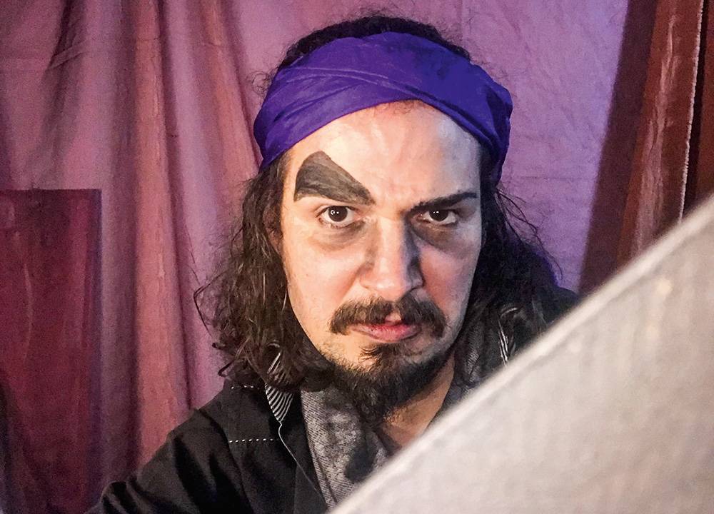 Um homem trajado de pirata com a sobrancelha pintada a levanta para cima