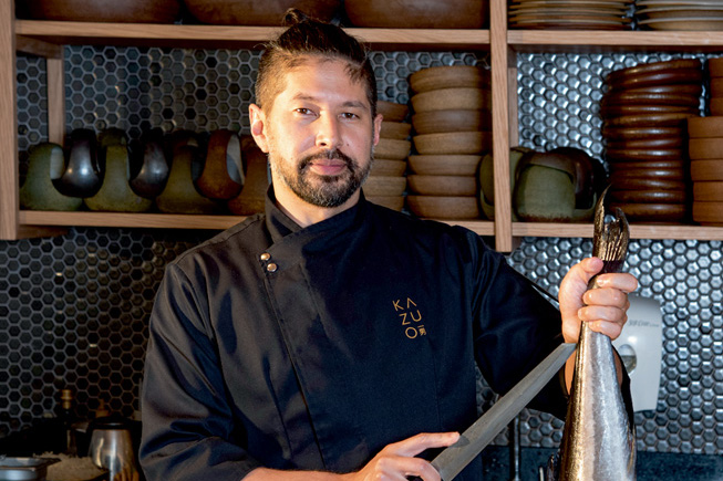 Chef Kazuo Harada posa segurando um peixe e uma faca