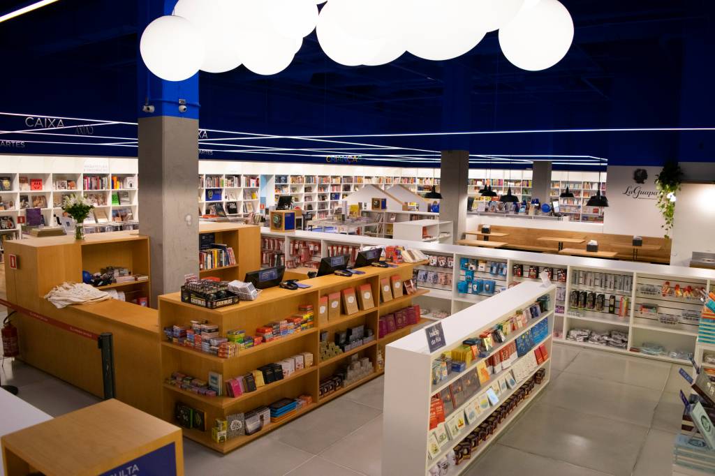 Livraria da Vila no Pátio Higienópolis. Foto exibe prateleiras de madeira e corredores da livraria bem iluminada com parede azulada.