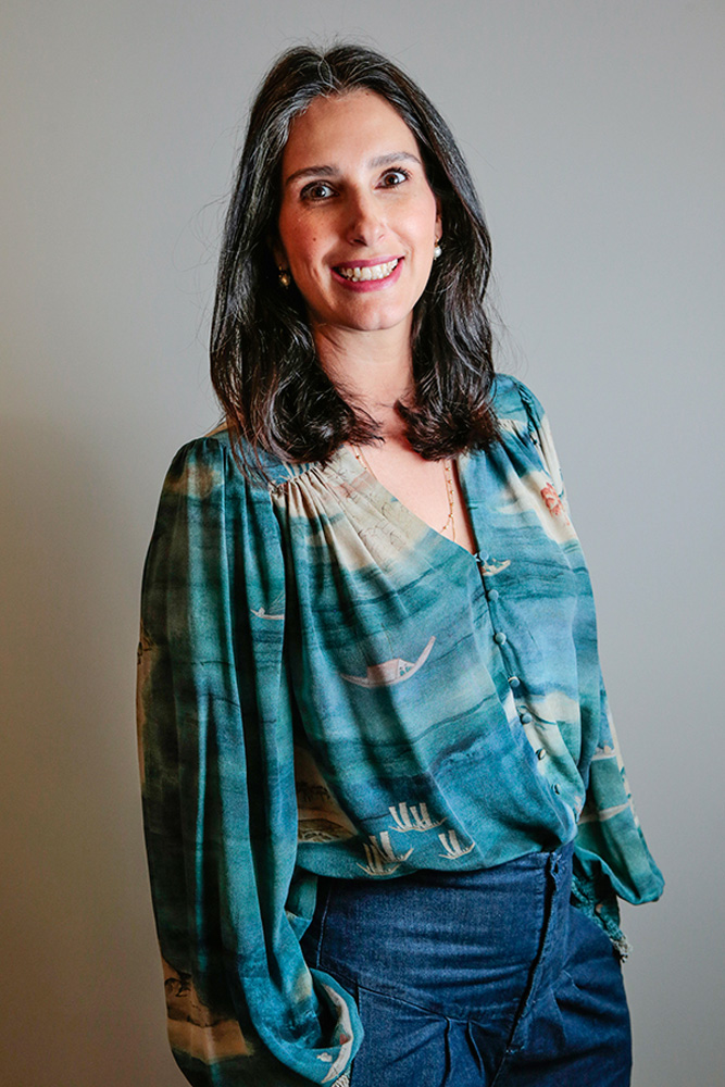 Maria-Fernanda-Quartiero-falando-sobre-indivíduos-a-tal-felicidade.jpg Maria Fernanda Quartiero sorrindo em estúdio. ela está utilizando uma blusa azul