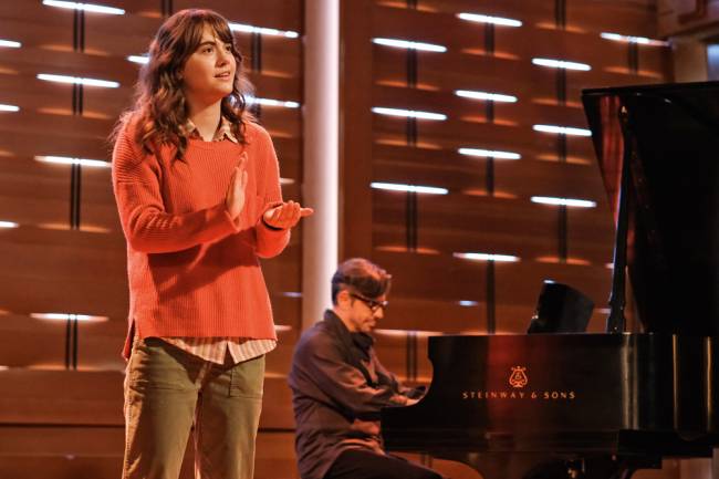 CodaPhoto: Mark Hill A imagem mostra Emilia Jones no papel de Ruby, em cima de um palco, fazendo gestos para cantar.