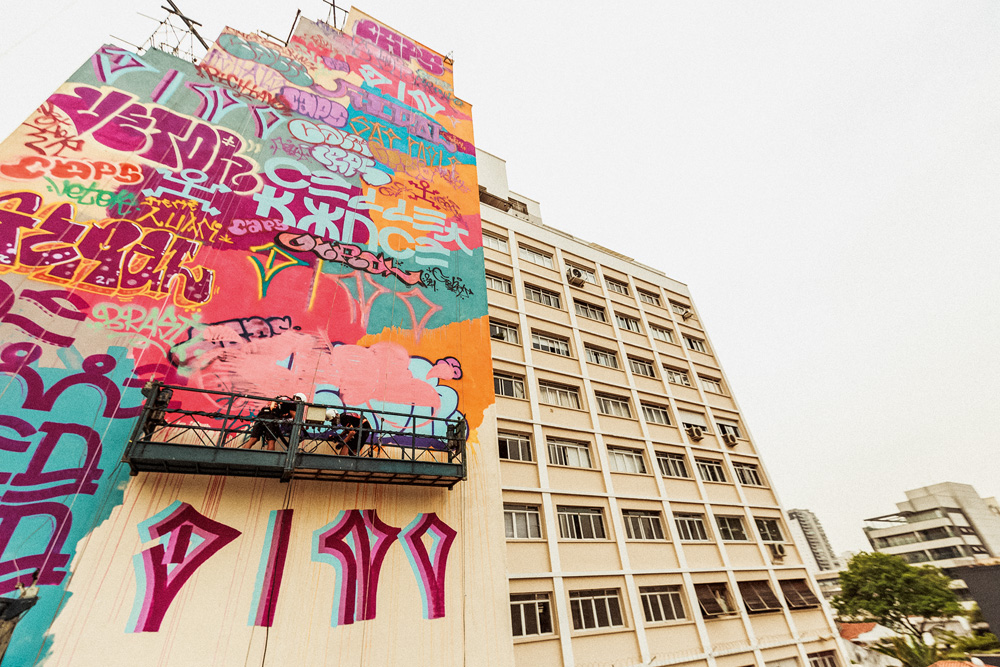 foto do nível do chão de lateral de prédio com grafite colorido sendo produzido