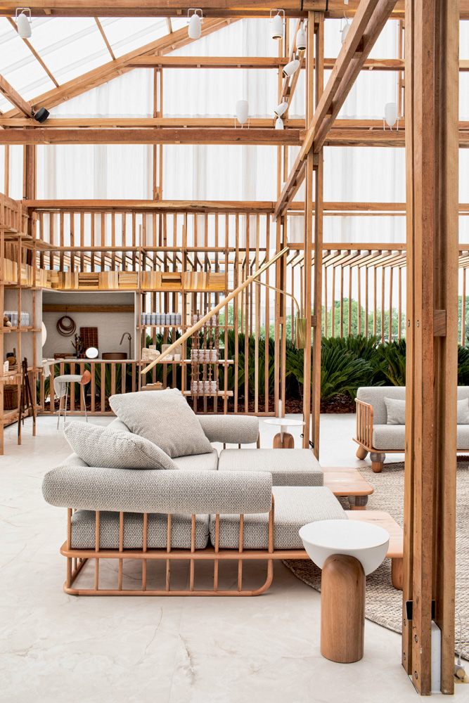 A imagem mostra uma sala com sofás e estruturada majoritariamente com madeiras, como em seus corrimões.