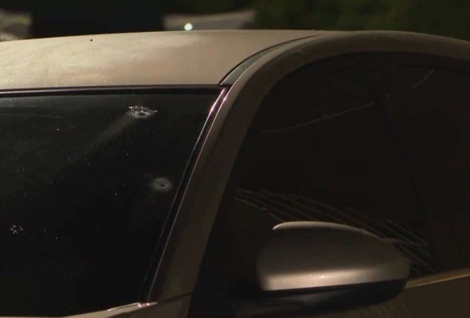 A imagem mostra o vidro frontal de um carro com duas marcas de bala.