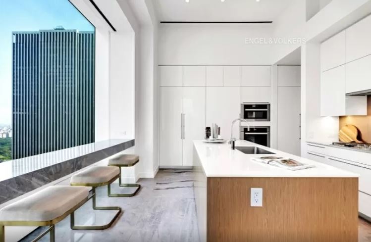 cozinha-432-park-avenue-arranha-céu-milionário-manhattan-problemas-processo-judicial cozinha americana com um grande balcão grande ao centro, armários ao fundo e janela com balcão para sentar à esquerda