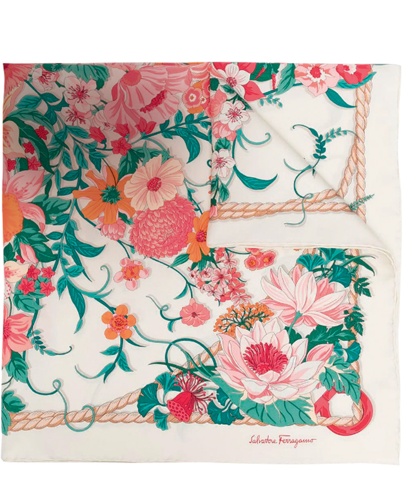 Um echarpe dobrado com estampa de ramos de folha verdes e flores rosa claro, pétalas e flores laranjas