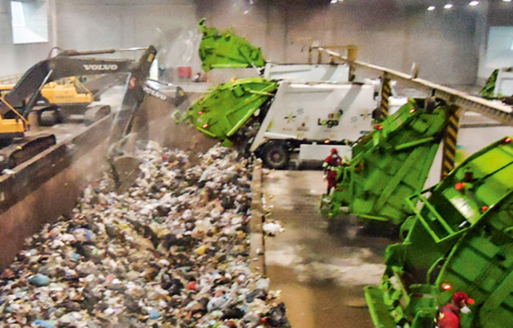 Uma estação de lixo. Caminhões jogam resíduos em um galpão