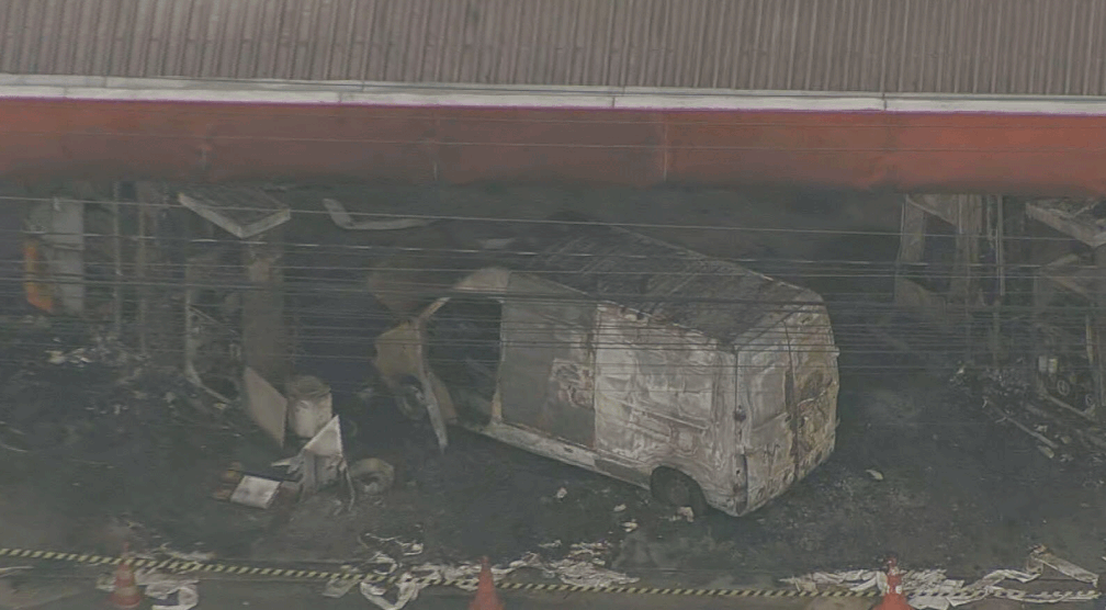 Imagem mostra van totalmente queimada e destroços ao redor dentro de posto de combustível