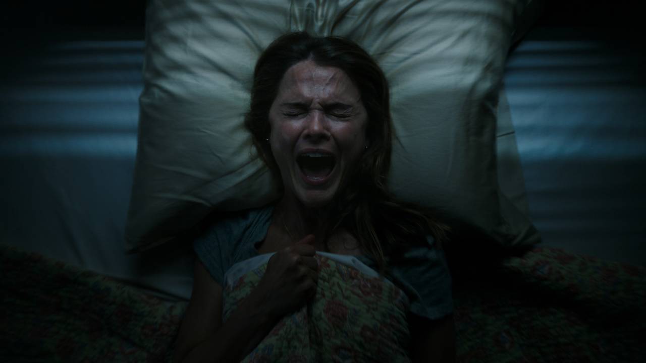 Uma mulher grita apavorada em sua cama