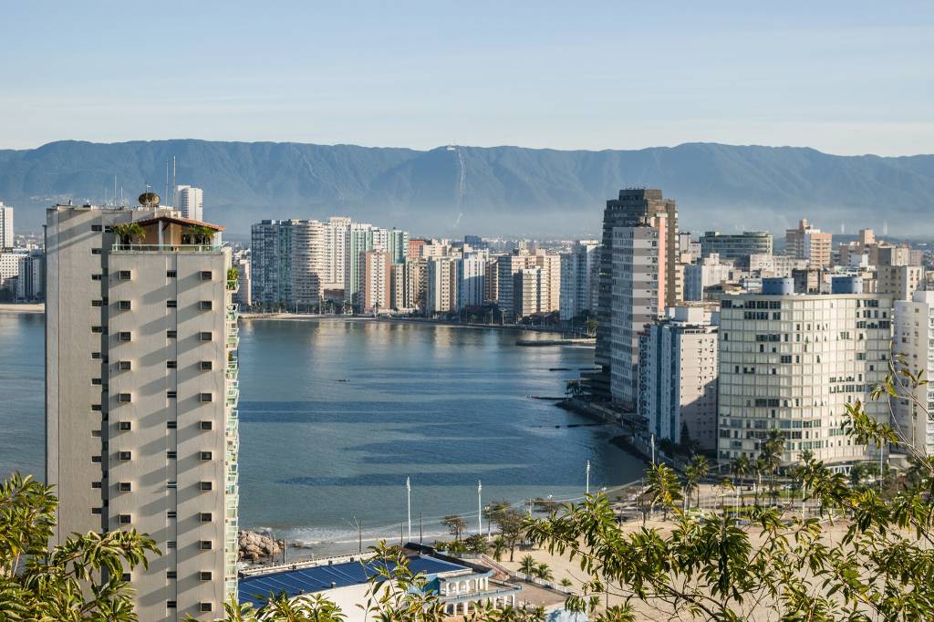 A foto mostra paisagem em São Vicente, com prédios e praia ao fundo