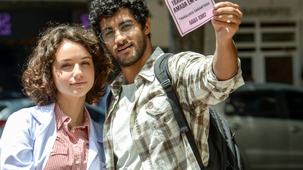 Um casal na rua com um bilhete escrito 'Trago a pessoa amada em 3 dias'