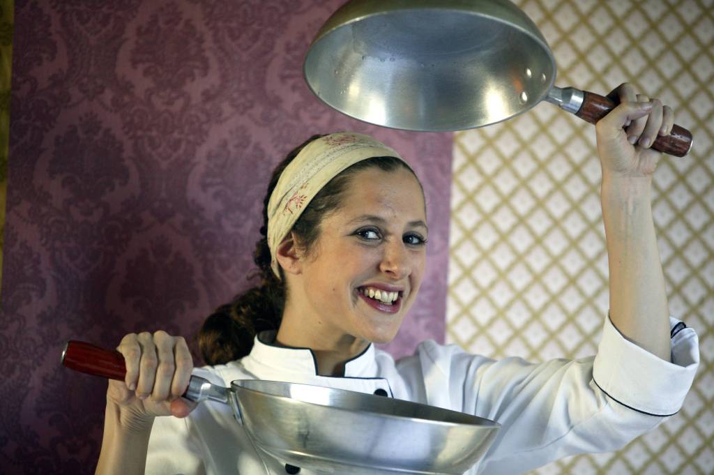 Andrea Kaufmann, chef de cozinha do restaurante AK Delicatessen, posa segurando duas frigideiras, uma em cada uma de suas mãos