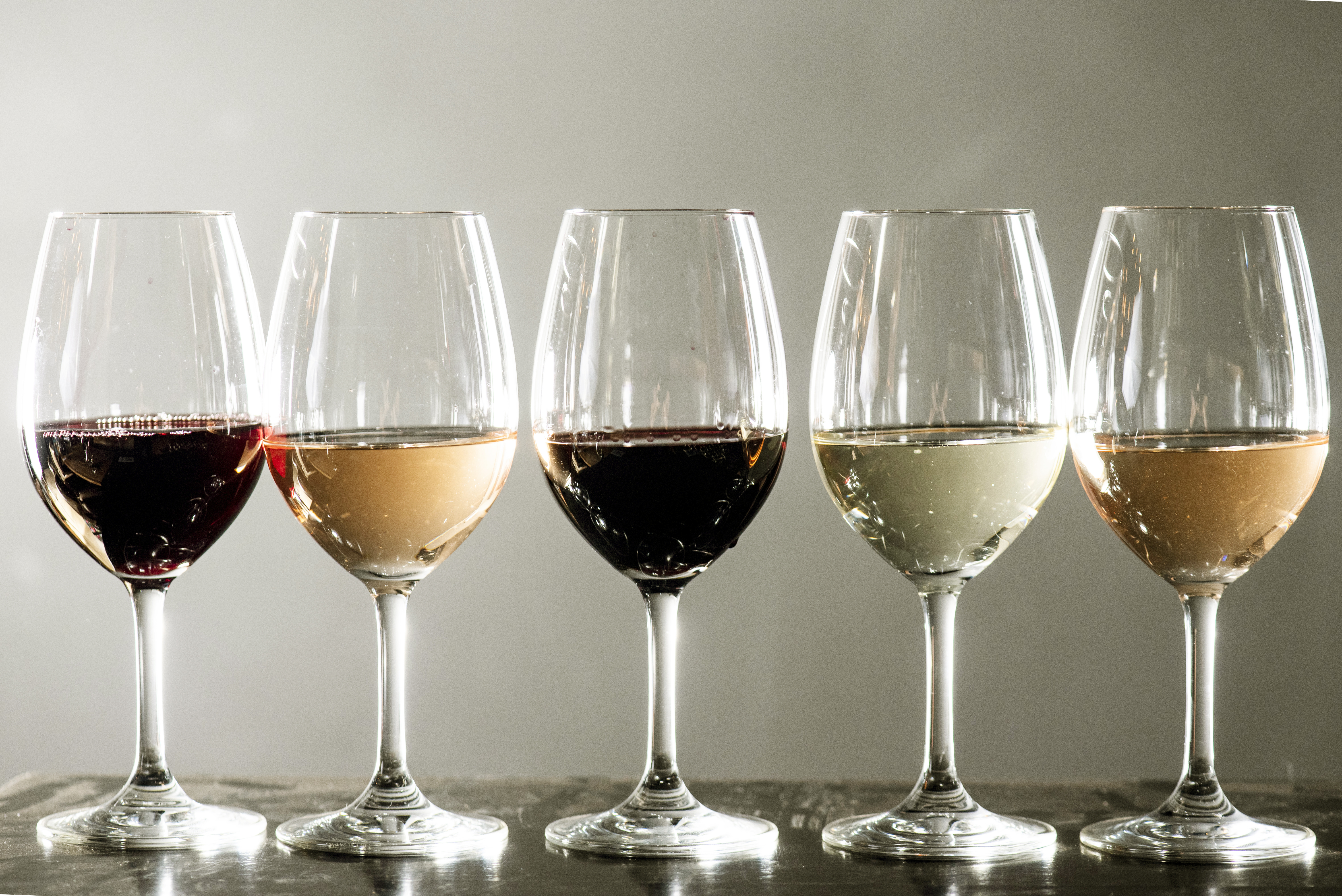Taças de vinhos com diferentes variedades alinhadas lado a lado.