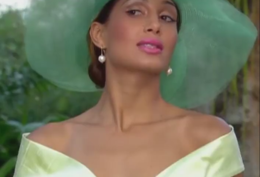 A imagem mostra Camila Pitanga em cena da novela Paraíso Tropical, em que usa um chapéu grande verde e uma roupa mostrando o dorso.
