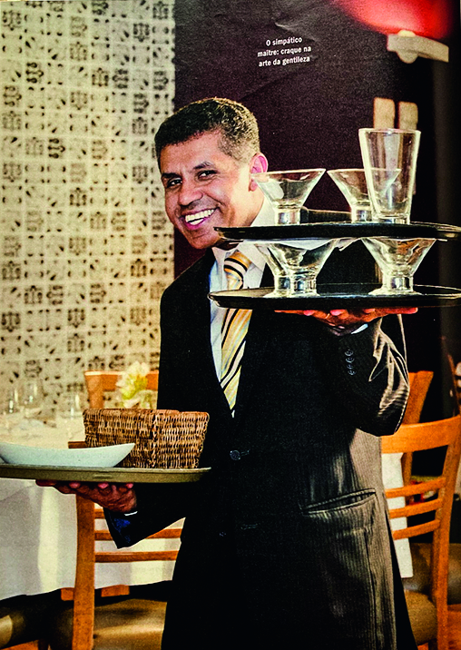 O maitre Jonas Soares segurando bandeja de ta&ccedil;as em uma m&atilde;o e outra com cestas de couvert.