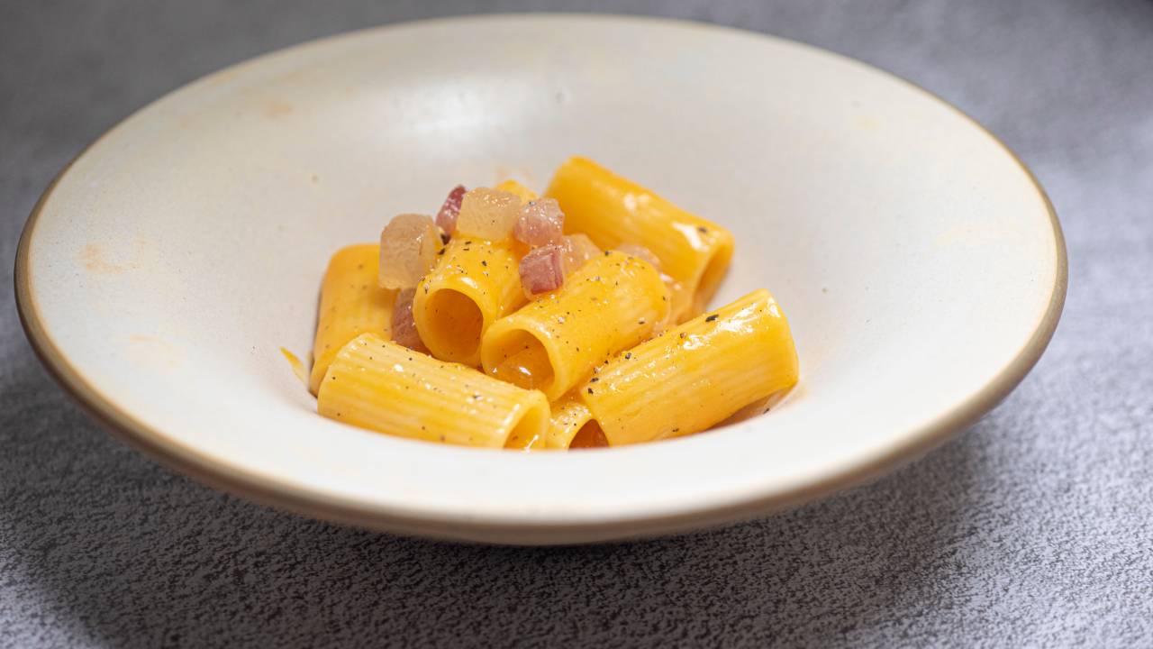 Prato fundo de cerâmica com rigatoni carbonara.