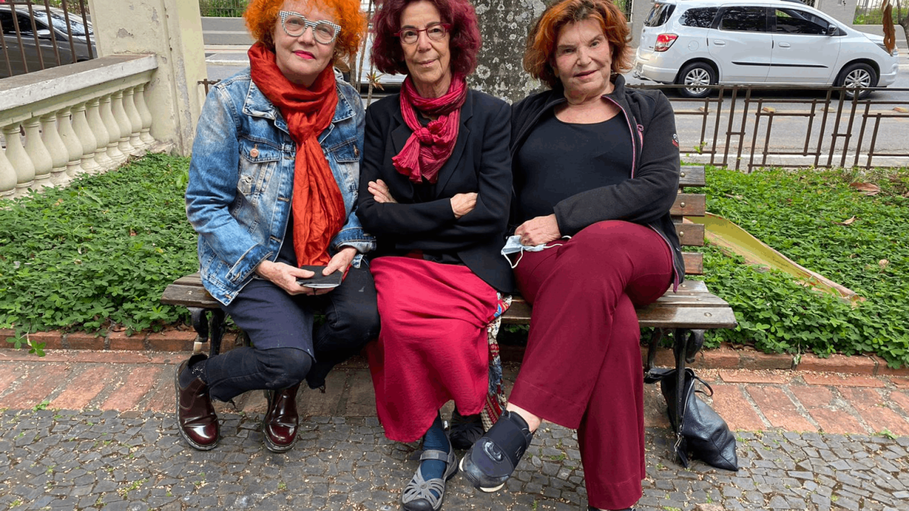 Artistas Fanny Feigenson, Fulvia Molina e Eva Castiel, sentadas em um banco na Oficina Cultural Oswald de Andrade