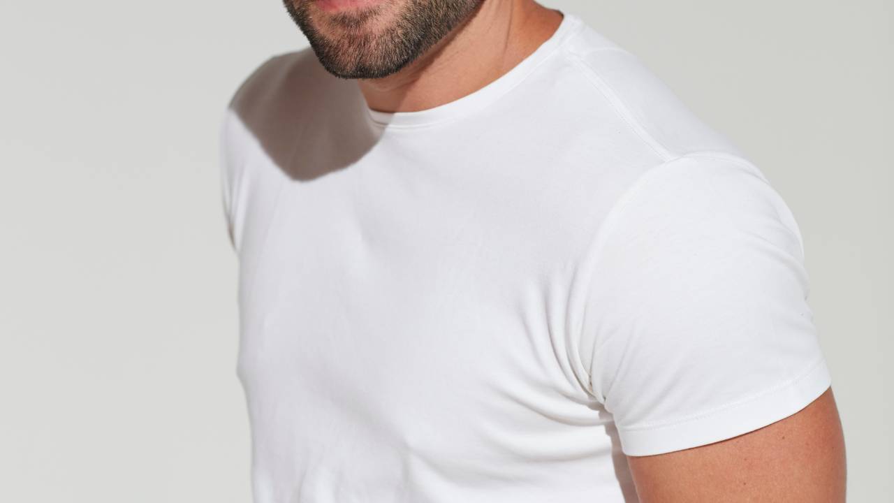 Produtor teatral Felipe Lima sorri para a foto e veste camiseta branca.