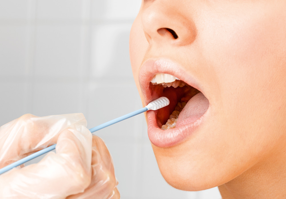 Pessoa segurando um cotonete de DNA na boca de uma jovem, close-up da boca, foto do estúdio