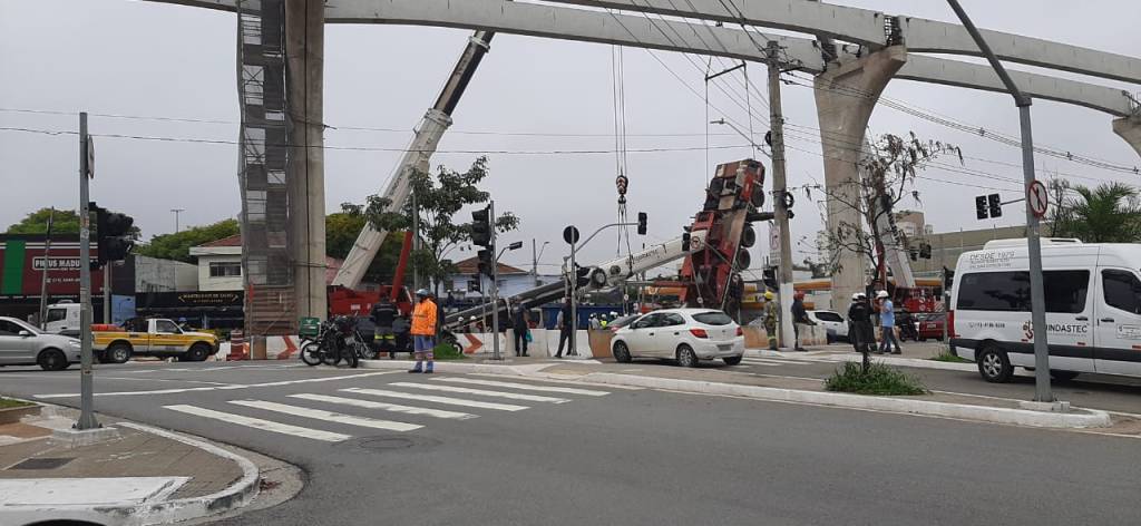 A imagem mostra um guindaste, inclinado com a parte da frente no chão, e as rodas suspensas no ar.