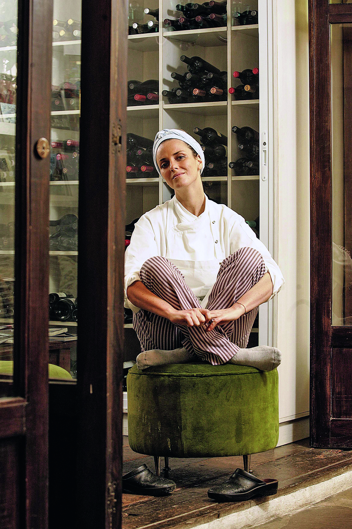 A chef Helena Rizzo sentada em pufe no salão do Maní.