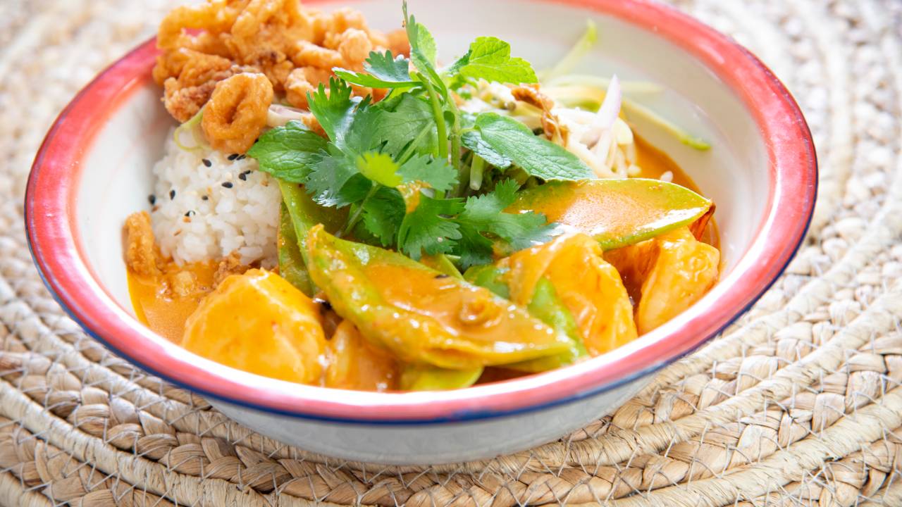 Curry servido junto de arroz e frutos do mar em uma cumbuca com detalhes na cor azul e na cor vermelha