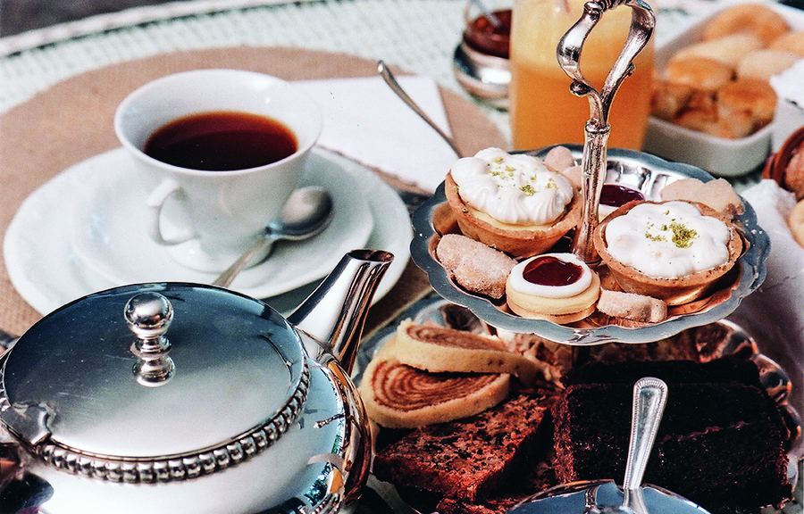 Mesa de ch&aacute; posta com bule, x&iacute;cara e docinhos.