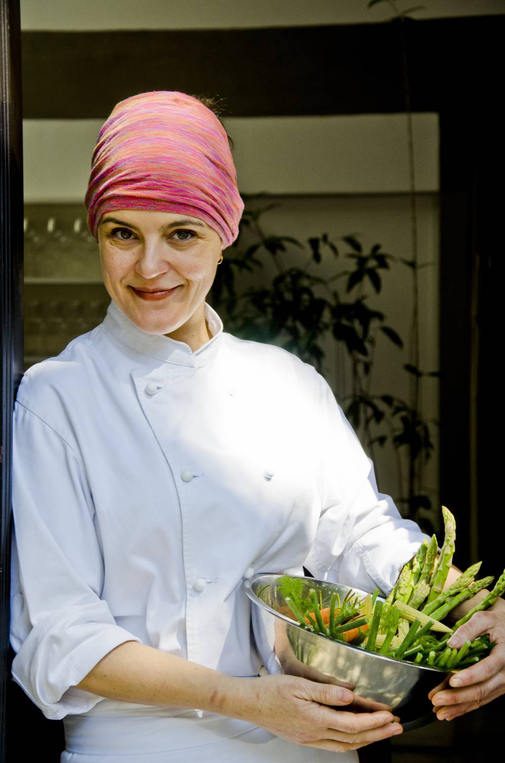 Viviane Gonçalves, chef de cozinha, posa segurando um recipiente metálico com aspargos