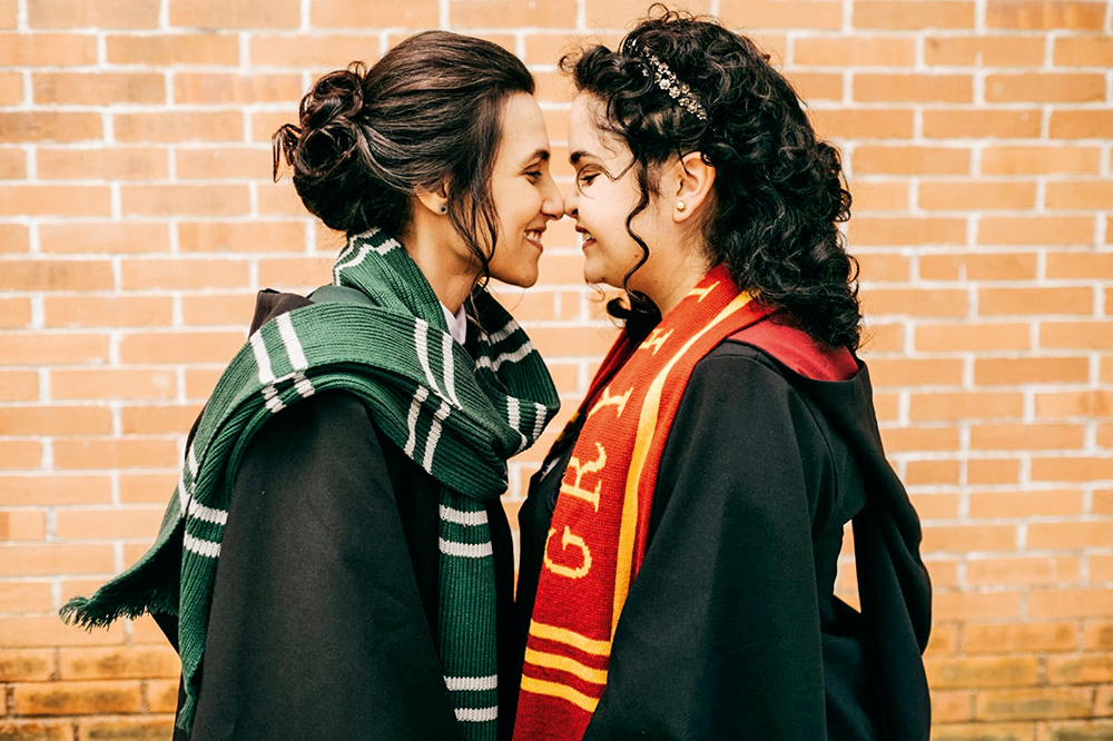 Carolina e Thais uma de frente para a outra sorrindo com os rostos encostados. elas estão de roupas do filme Harry Potter