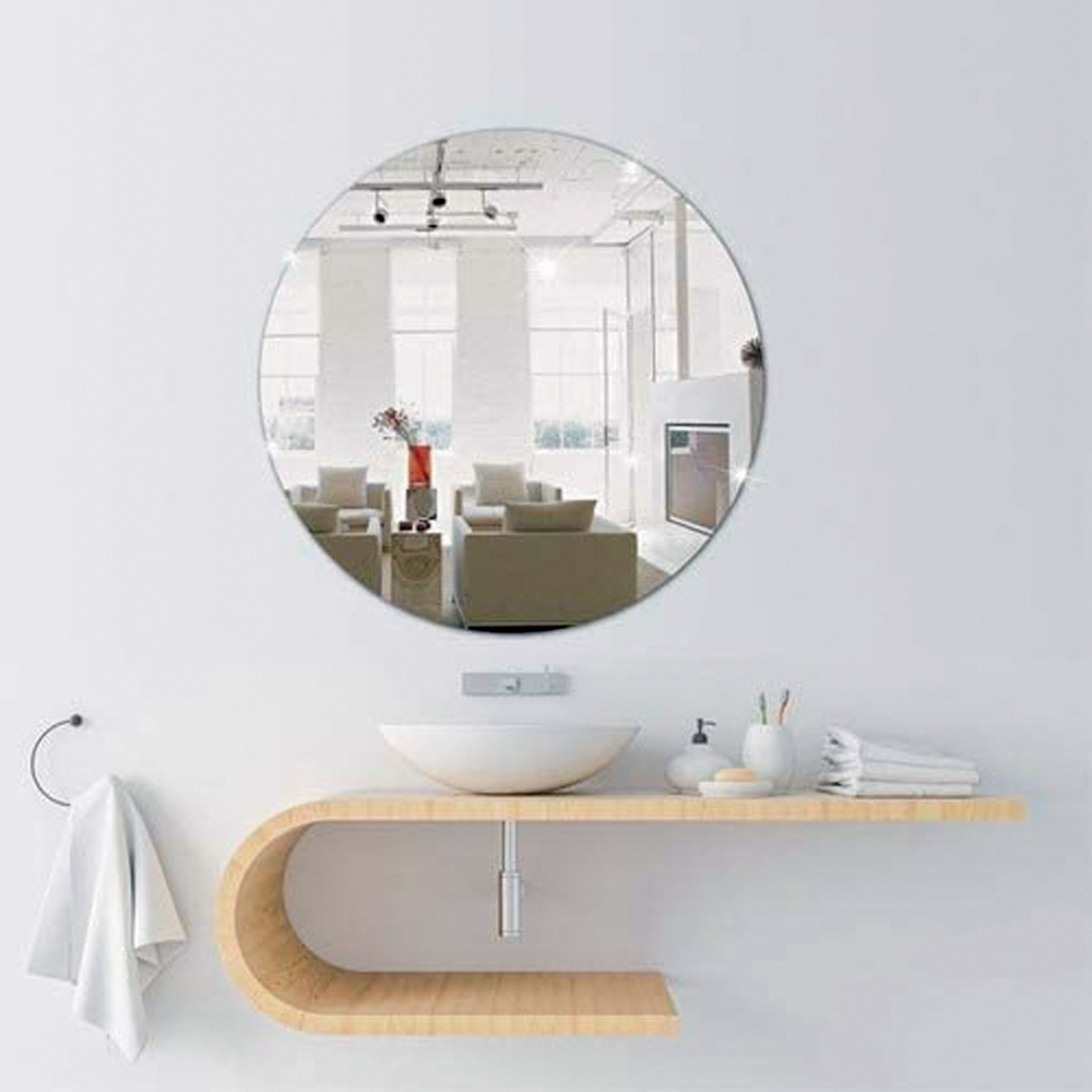 Em um banheiro, há um espelho redondo pendurado na parede branca. Há também uma estrutura para a pia e outra para uma toalha